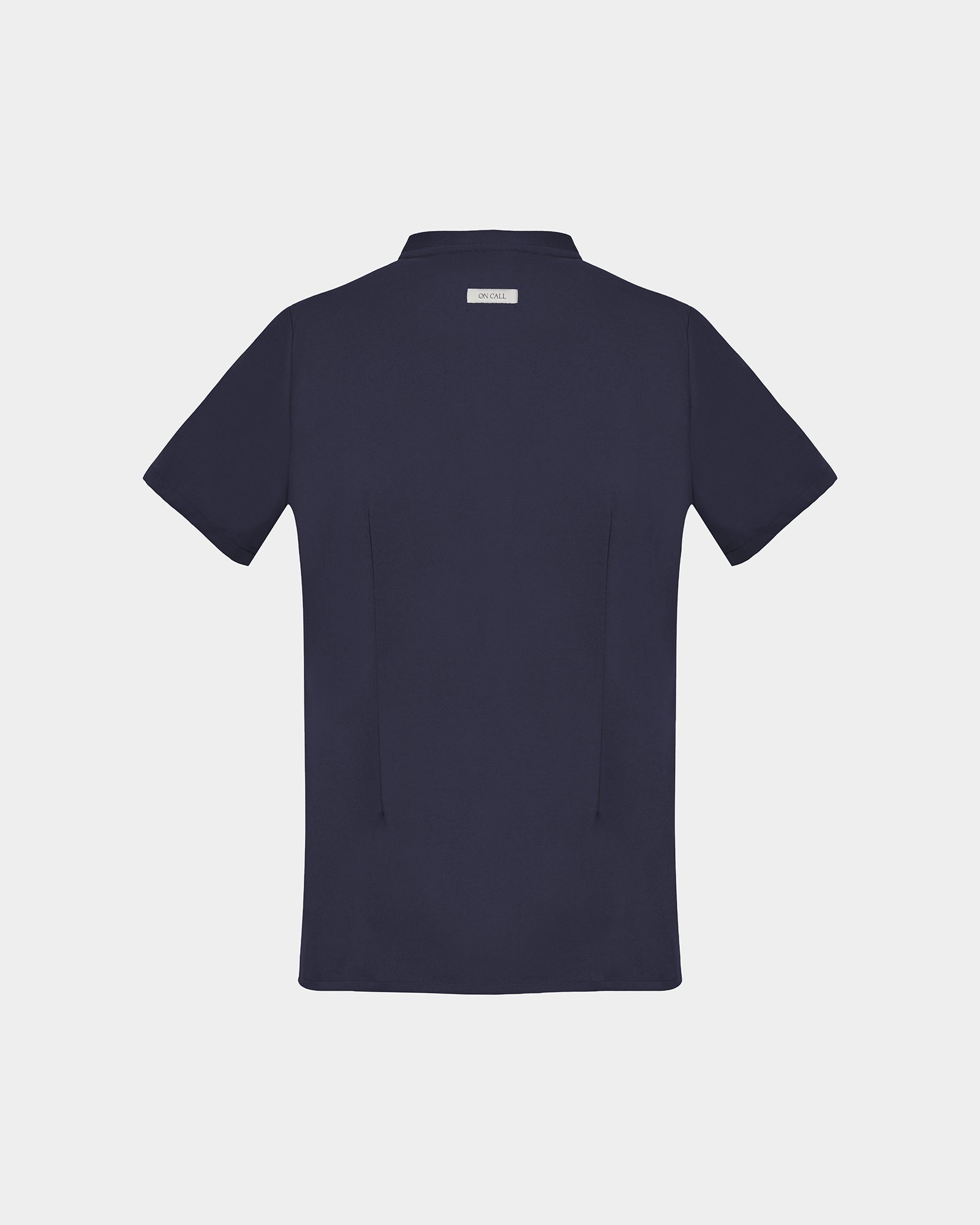 A dark navy blue short-sleeve scrub shirt shown from the back, featuring two darts, centered on a light gray background.