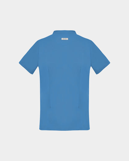 A short-sleeve scrub shirt in a solid medium blue color, shown from the back, featuring two darts, on a light gray background.