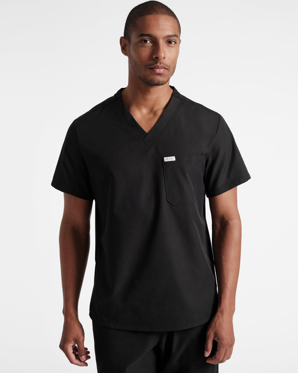 A man wearing a black scrub top with a V-neck and a chest pocket.