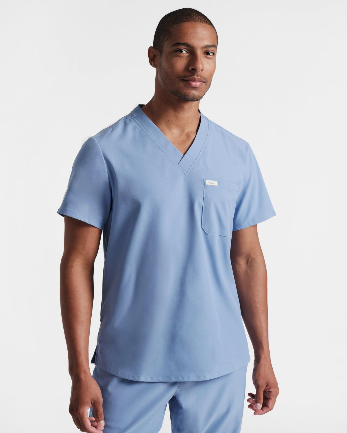 Man wearing a classic light blue v-neck scrub shirt with a chest pocket.