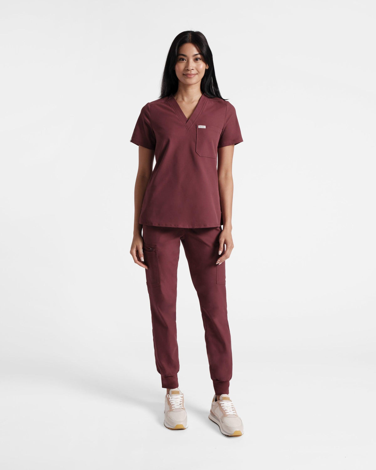Woman in a deep red v-neck scrub shirt and matching cargo jogger scrub pants. 
