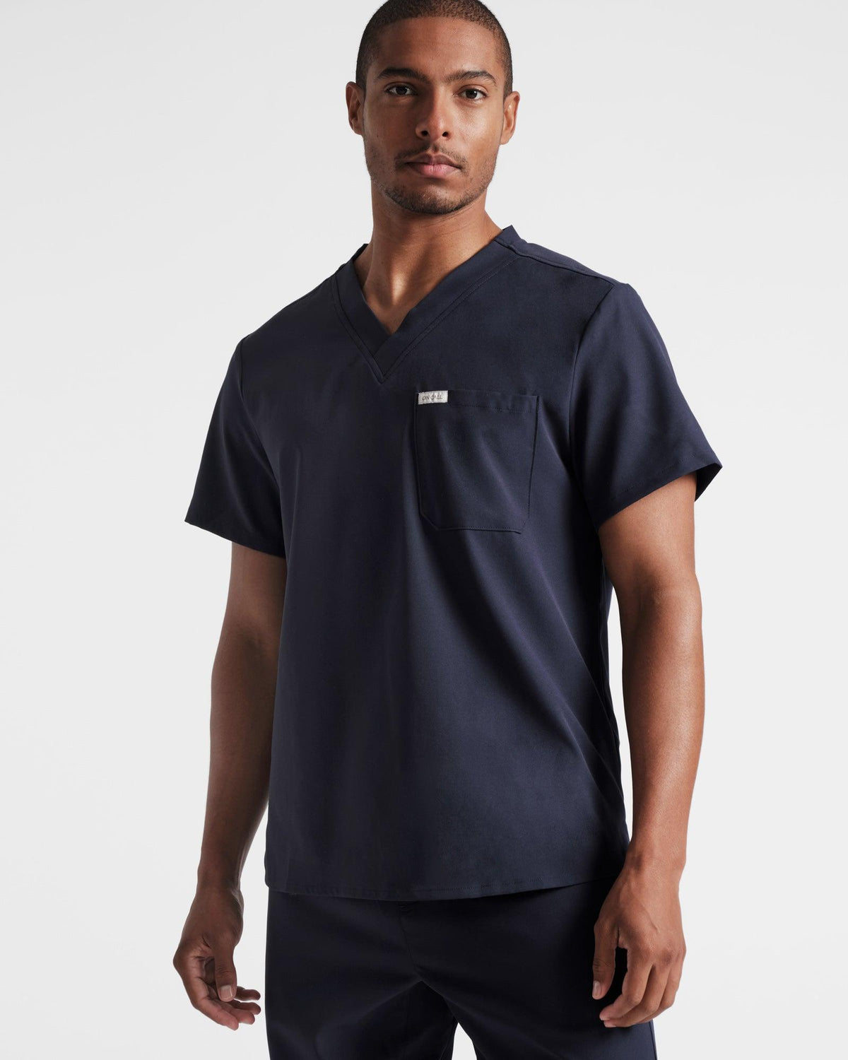 Man wearing a navy v-neck scrub shirt with a chest pocket.