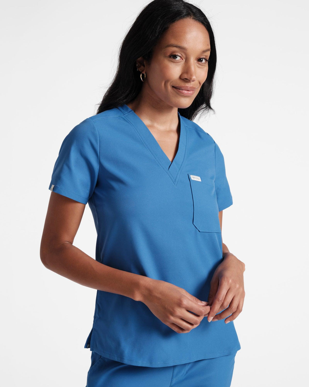 Woman in bright blue v-neck scrub shirt with a chest pocket.