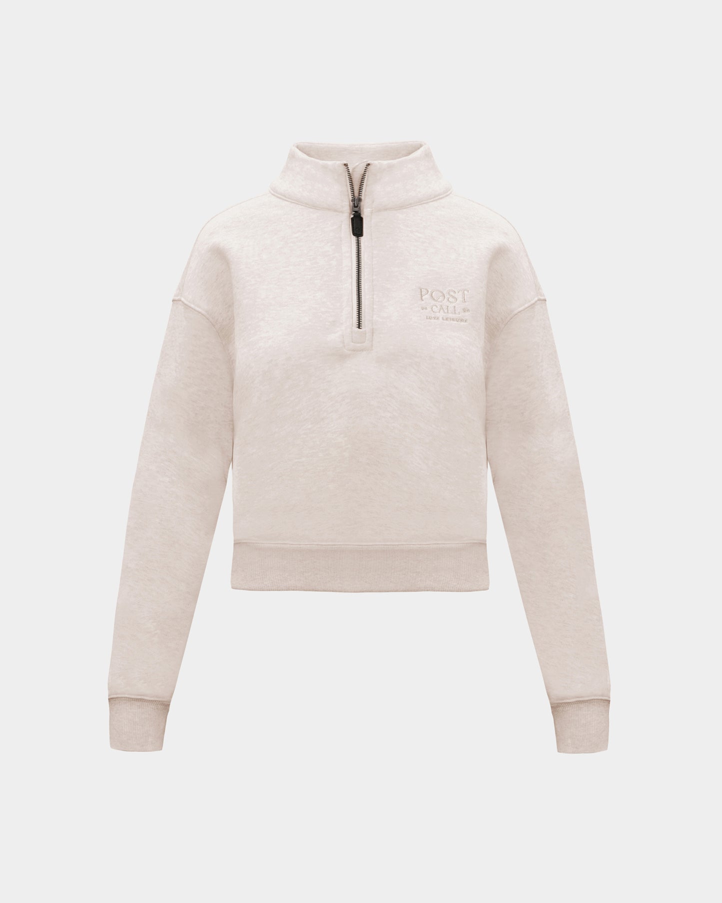 A heather beige half-zip sweatshirt with  small tonal embroidered logo on the left chest, displayed on a clean light gray background.