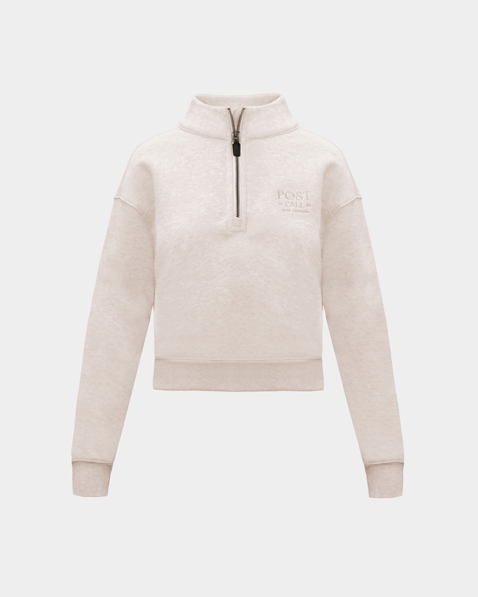 A heather beige half-zip sweatshirt with  small tonal embroidered logo on the left chest, displayed on a clean light gray background.