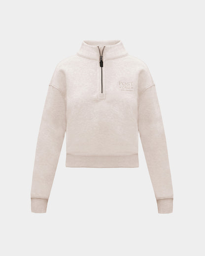 A heather beige half-zip sweatshirt with  small tonal embroidered logo on the left chest, displayed on a clean light gray background.