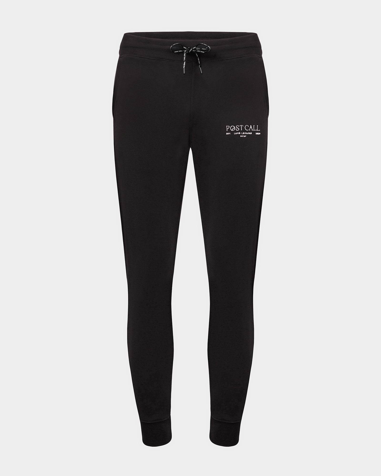 Black jogger lounge pants with ankle cuffs, a logo drawstring, and a contrast embroidered 'POST CALL' logo in white on the left thigh.