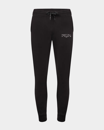 Black jogger lounge pants with ankle cuffs, a logo drawstring, and a contrast embroidered 'POST CALL' logo in white on the left thigh.