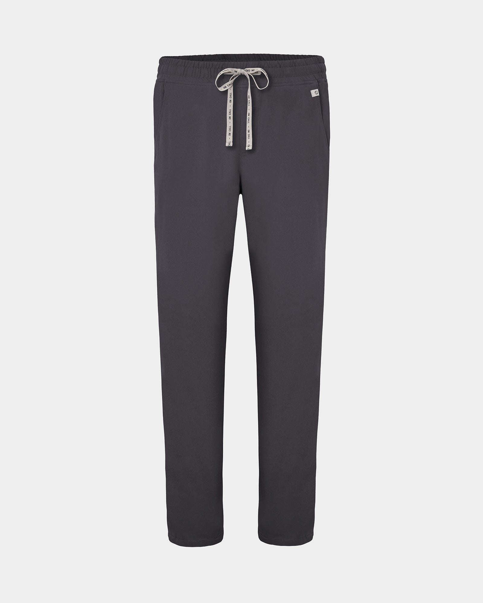 Dark grey straight leg scrub pants with a white logo drawstring and a small white logo on the left hip, shown against a light gray background.