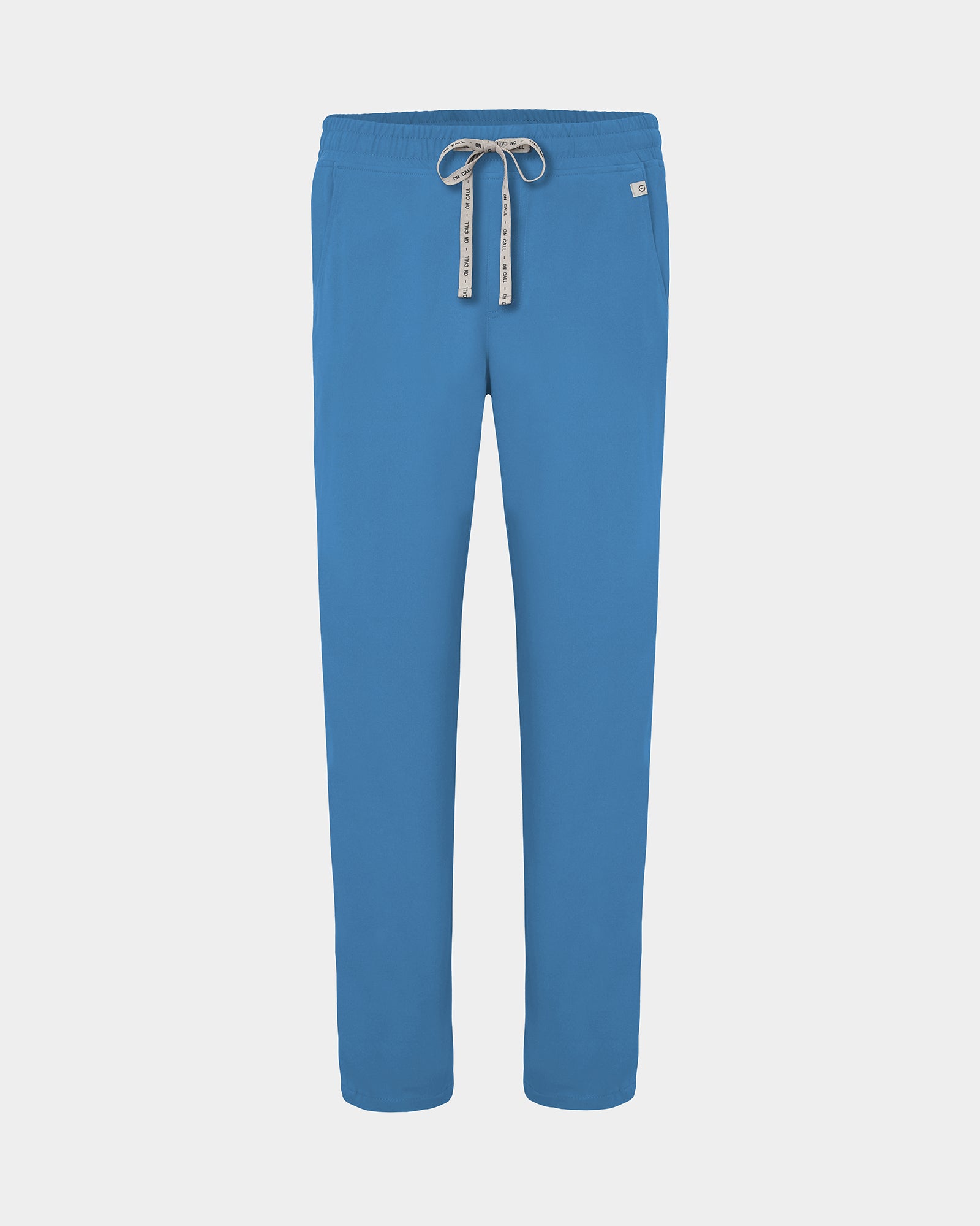 A pair of bright blue scrub pants with a white drawstring featuring black lettering, shown against a light gray background.
