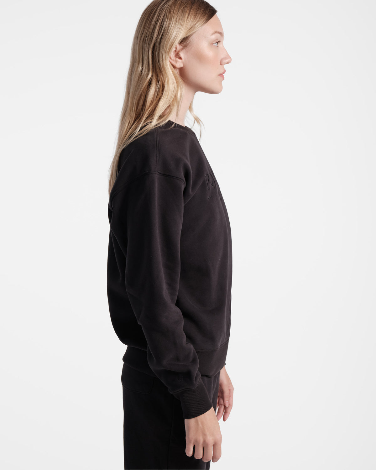 Side view of woman wearing unisex black crewneck sweatshirt.