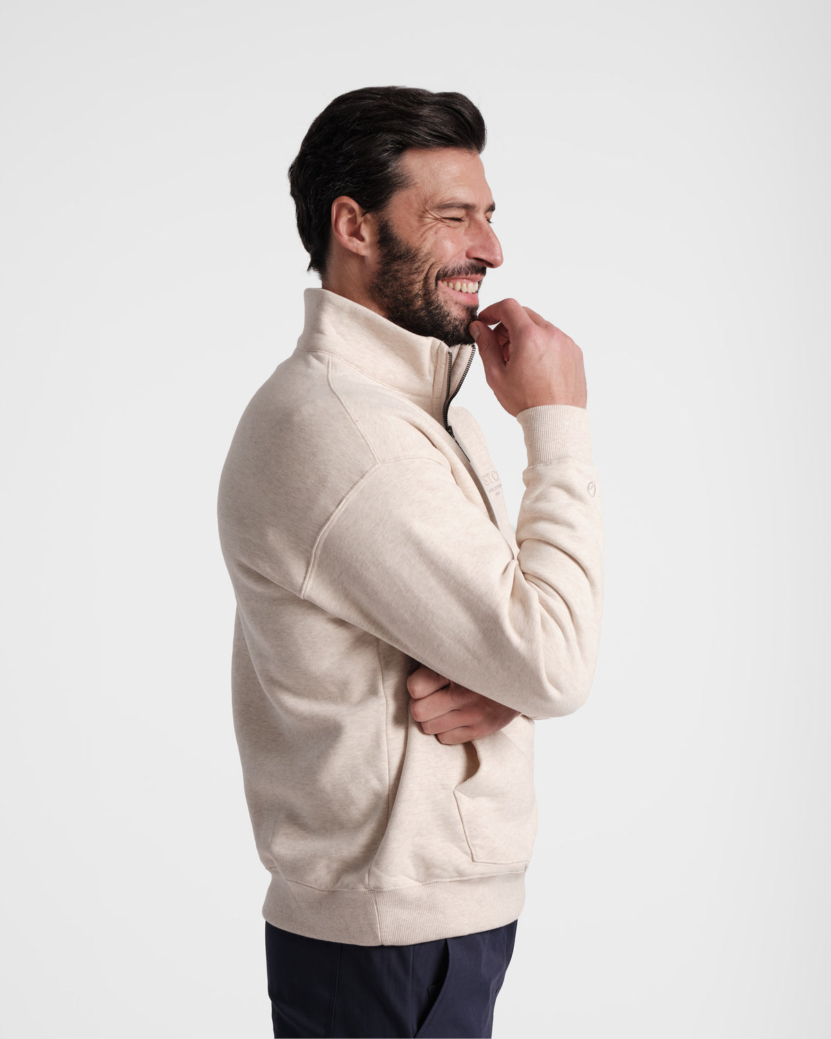 Side view of man wearing heather beige half zip sweatshirt with a kangaroo pocket.