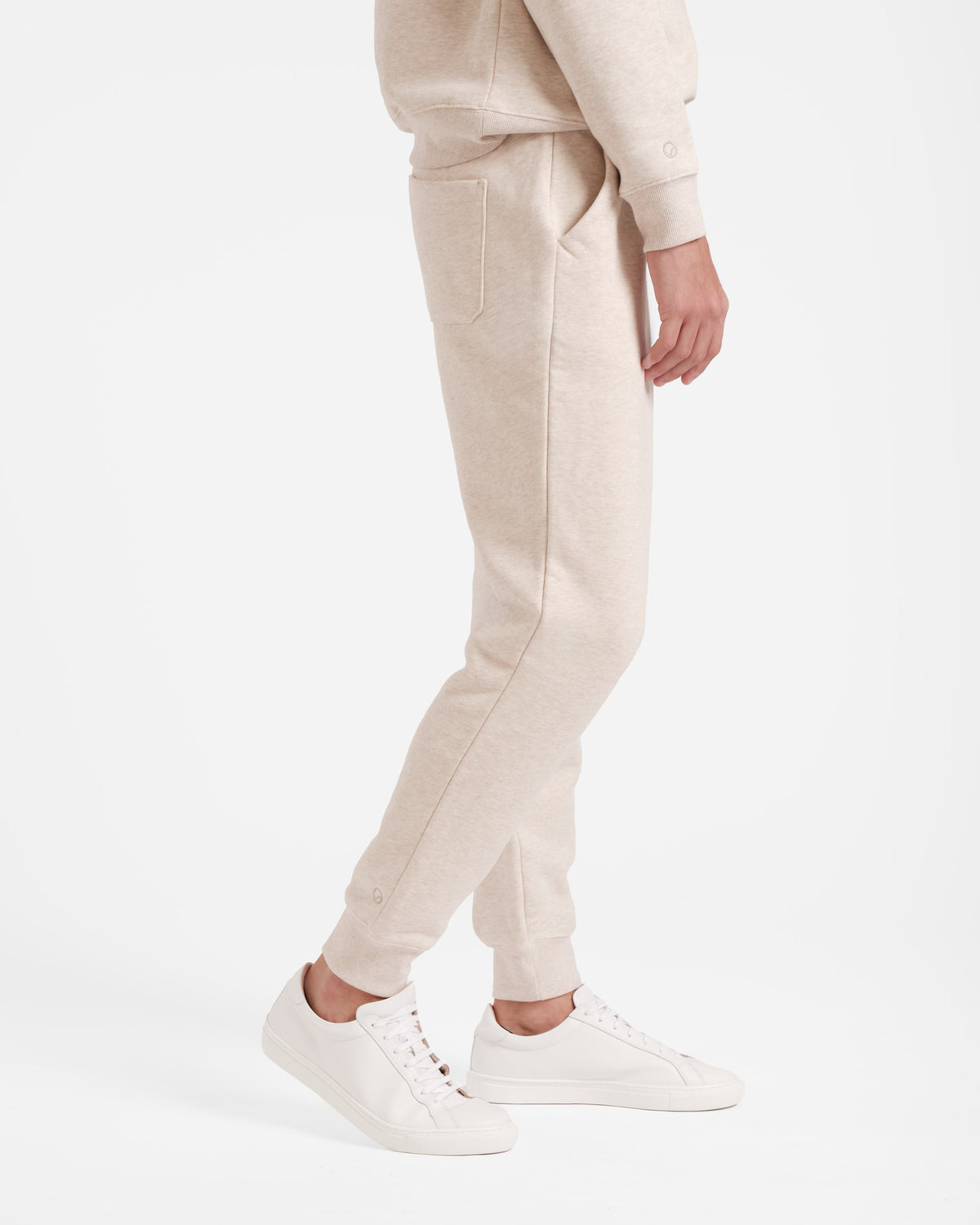Side view of man wearing heather beige jogger sweatpants with stretch ankle cuffs, side pockets, and back pocket.