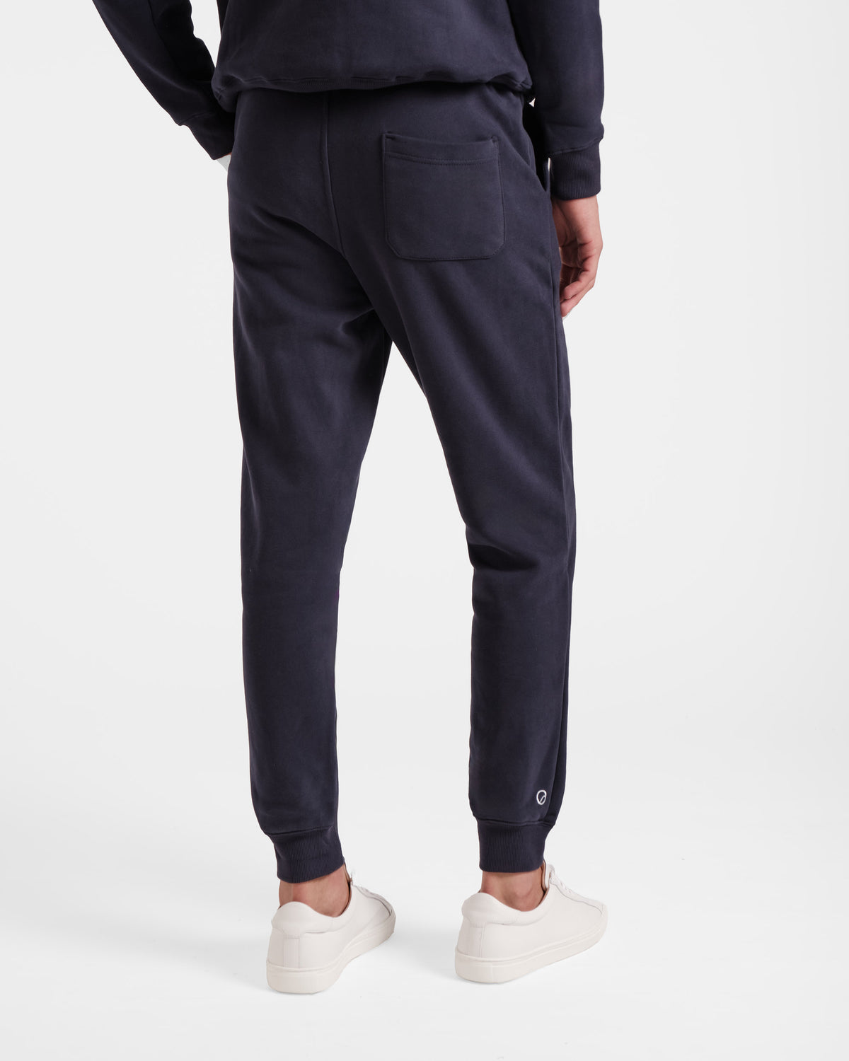 Back side view of man wearing navy jogger sweatpants with back pocket.