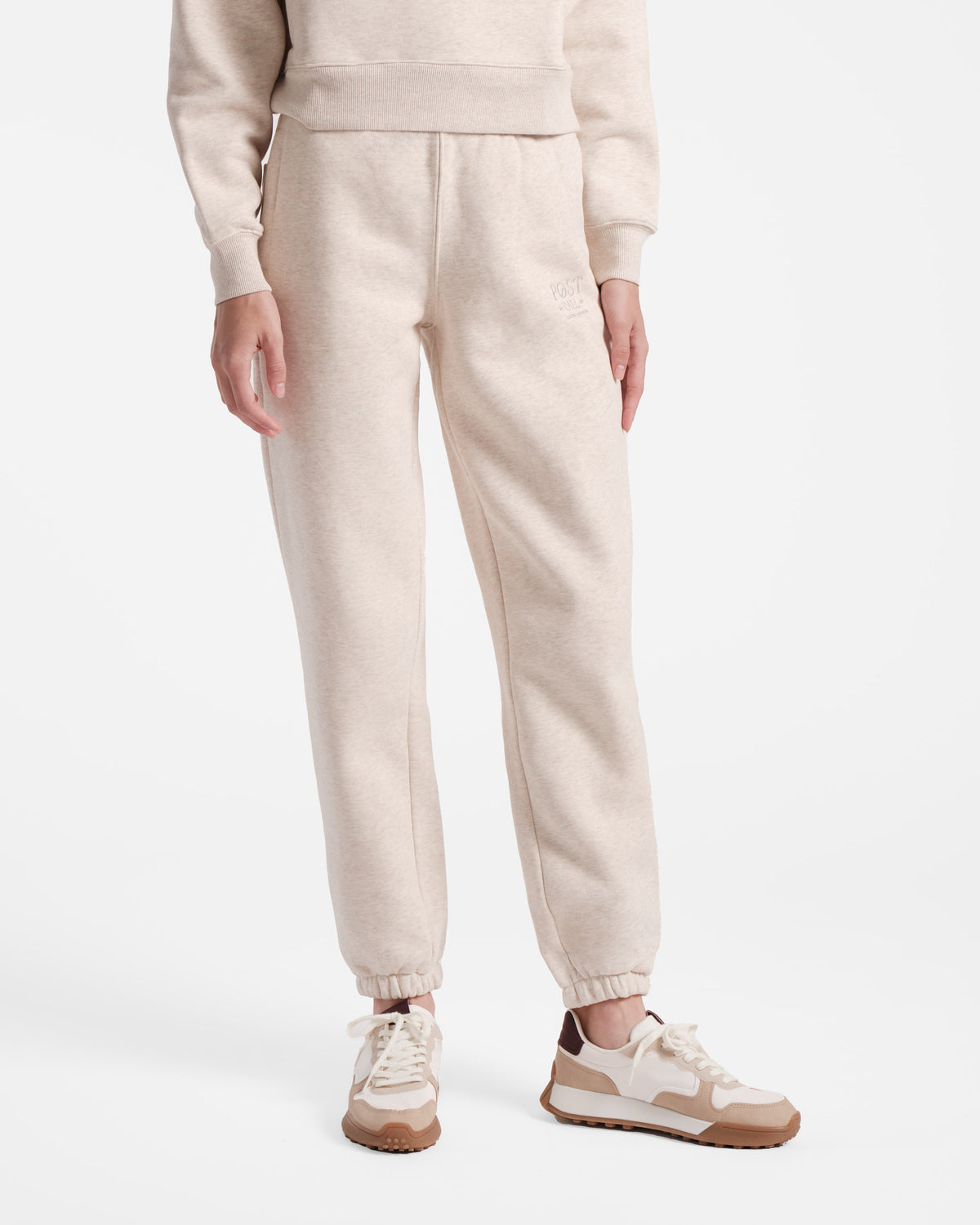 Model wearing women's jogger in heather beige with elasticated ankle cuffs.