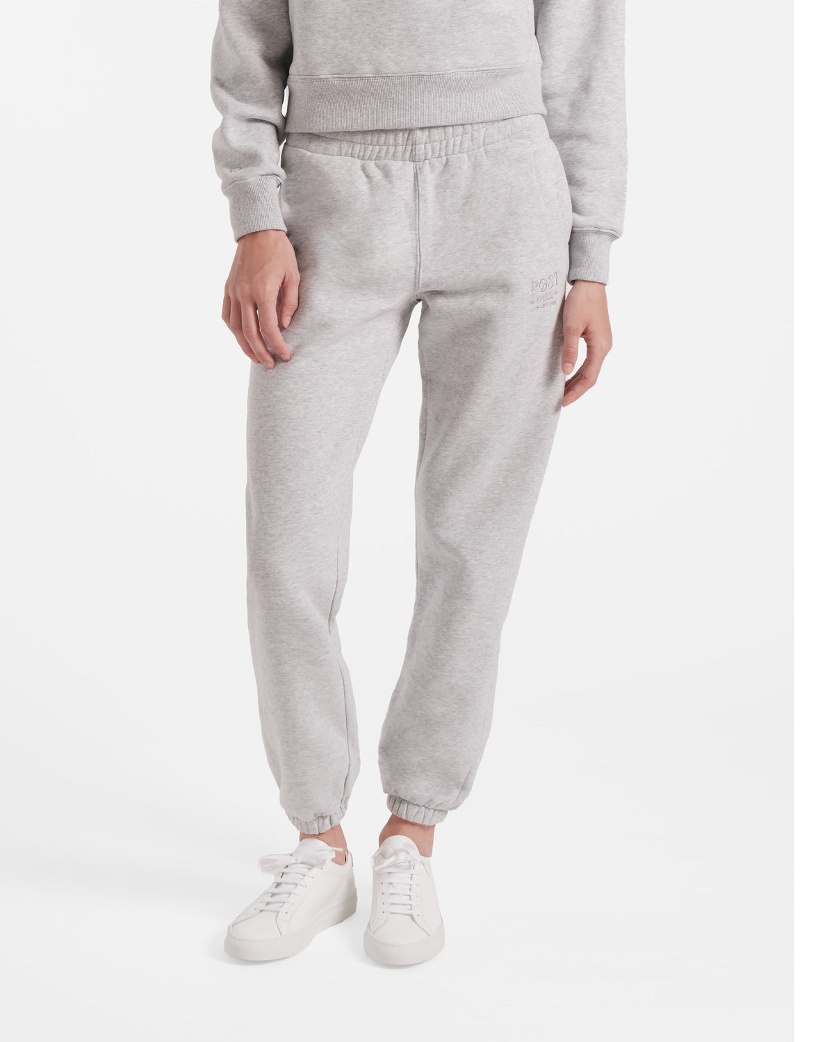 Model wearing women's jogger sweatpants in heather grey with elasticated cuffs and tonal logo embroidery.