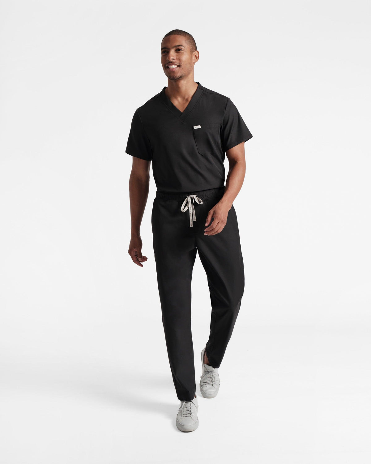 Model wearing men's black straight leg scrub pants with matching shirt.