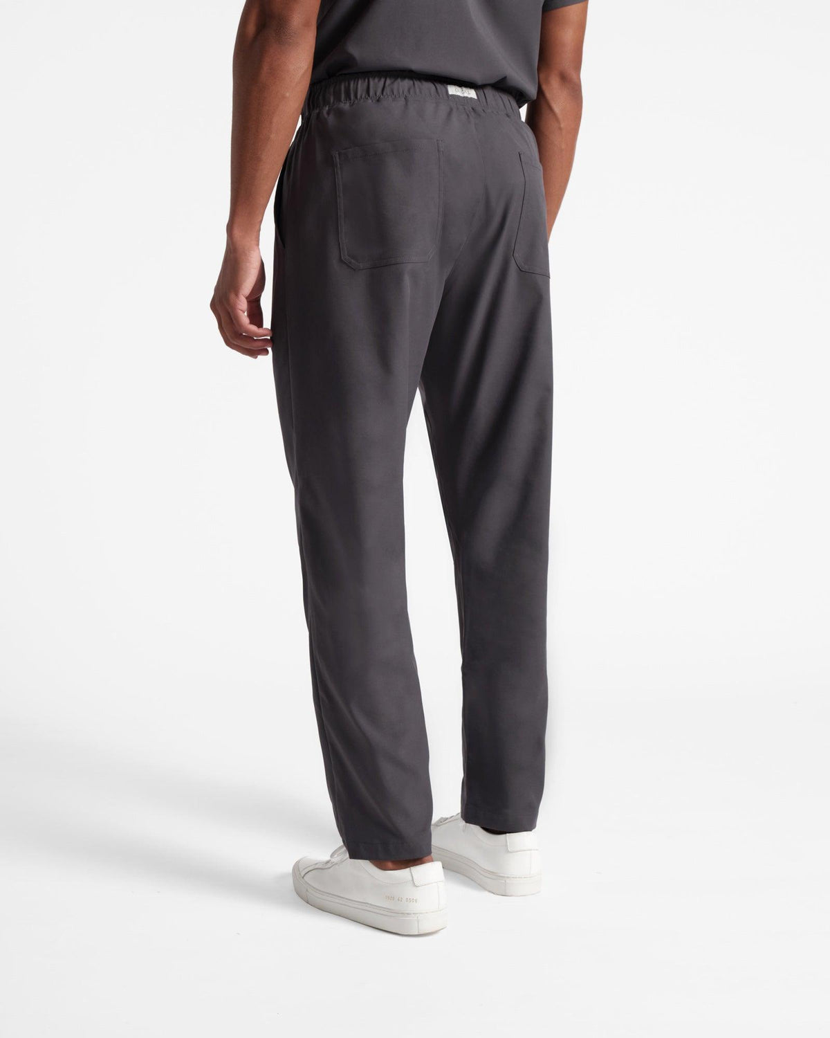 Back side view of man in dark grey straight leg scrub pants with two back pockets. 