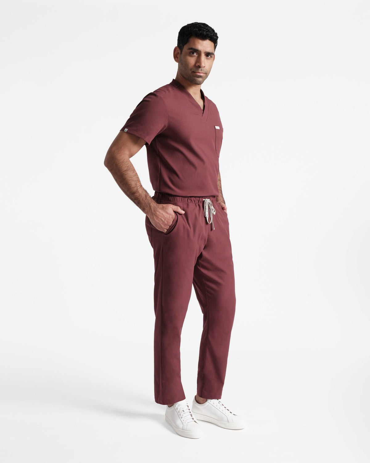Man in deep red straight leg scrub pants and a matching v-neck scrub shirt tucked in. 