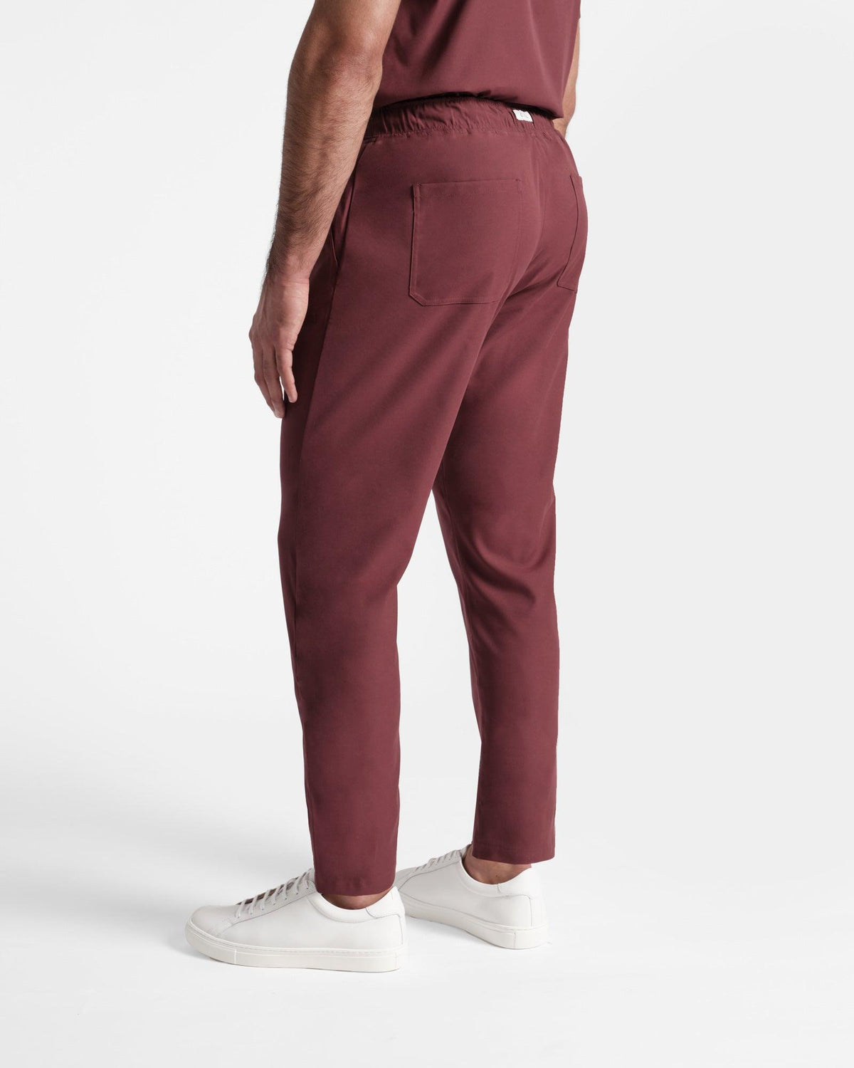 Angled back side view of man in deep red straight leg scrub pants with two back pockets. 