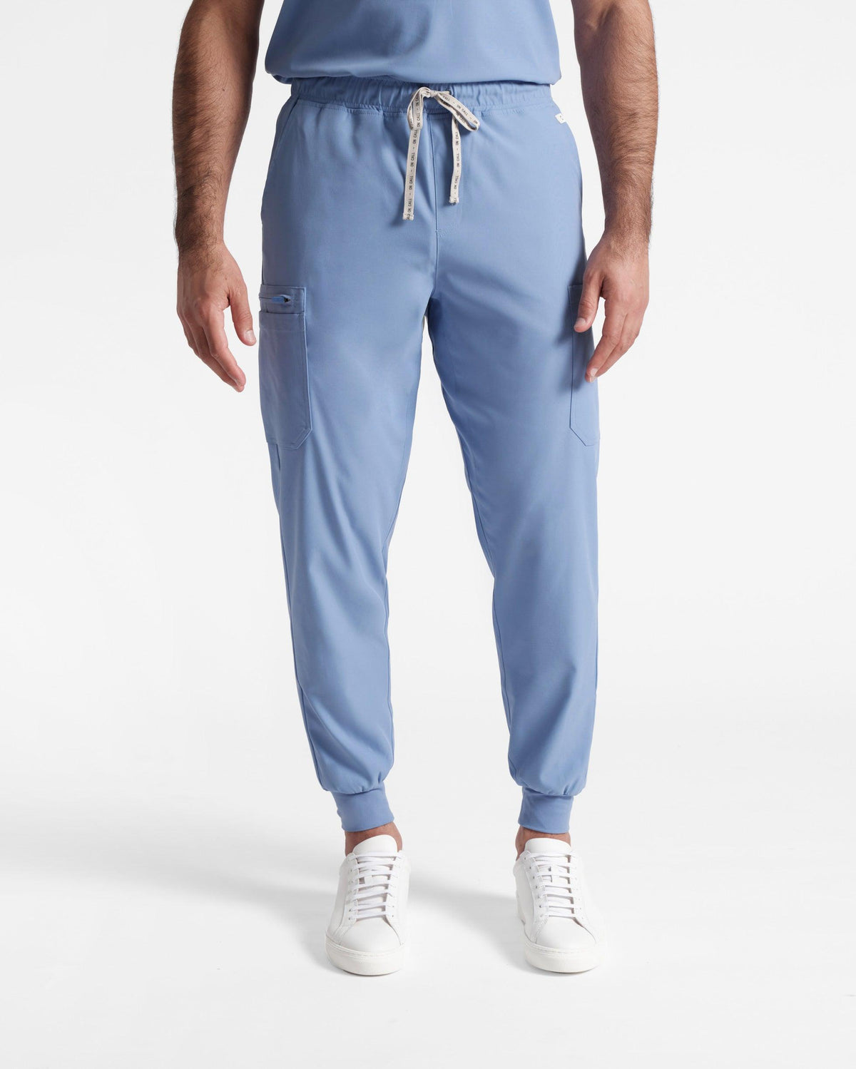 Man in light blue cargo jogger scrub pants with soft ribbed ankle cuffs. 