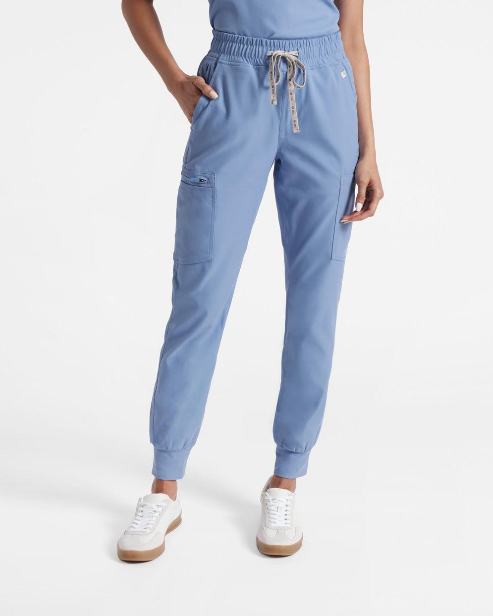 Model wearing women's light blue jogger cargo scrub pants with hand in waist pocket.