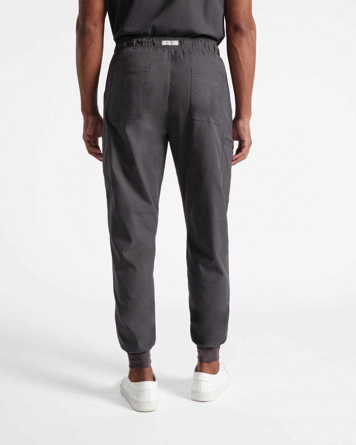 Back side view of man in dark grey cargo jogger scrub pants with two back pockets. 