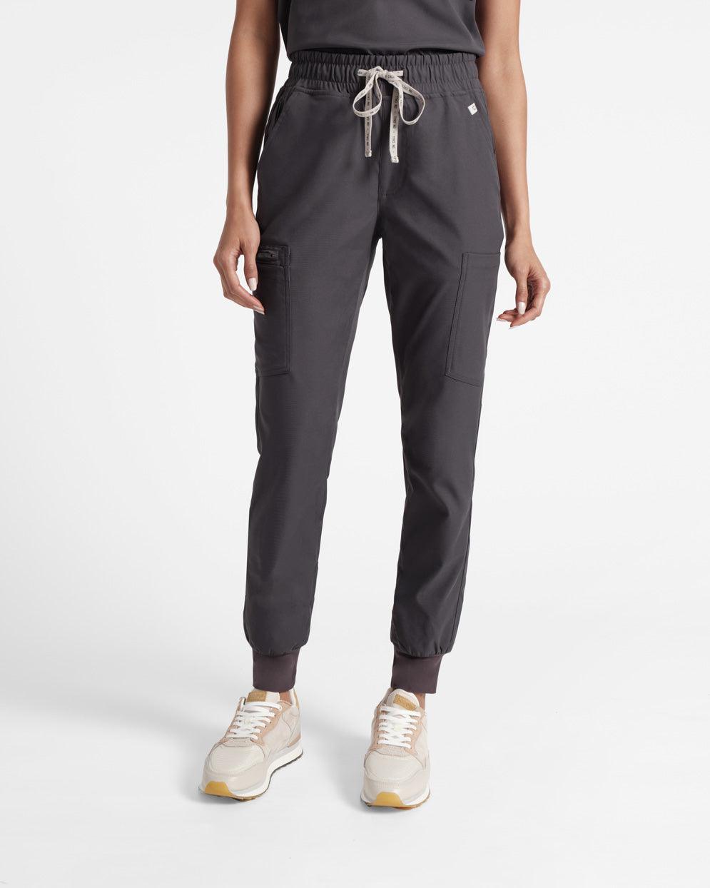 Woman in dark grey cargo jogger scrubs with soft ribbed elasticated ankle cuffs. 
