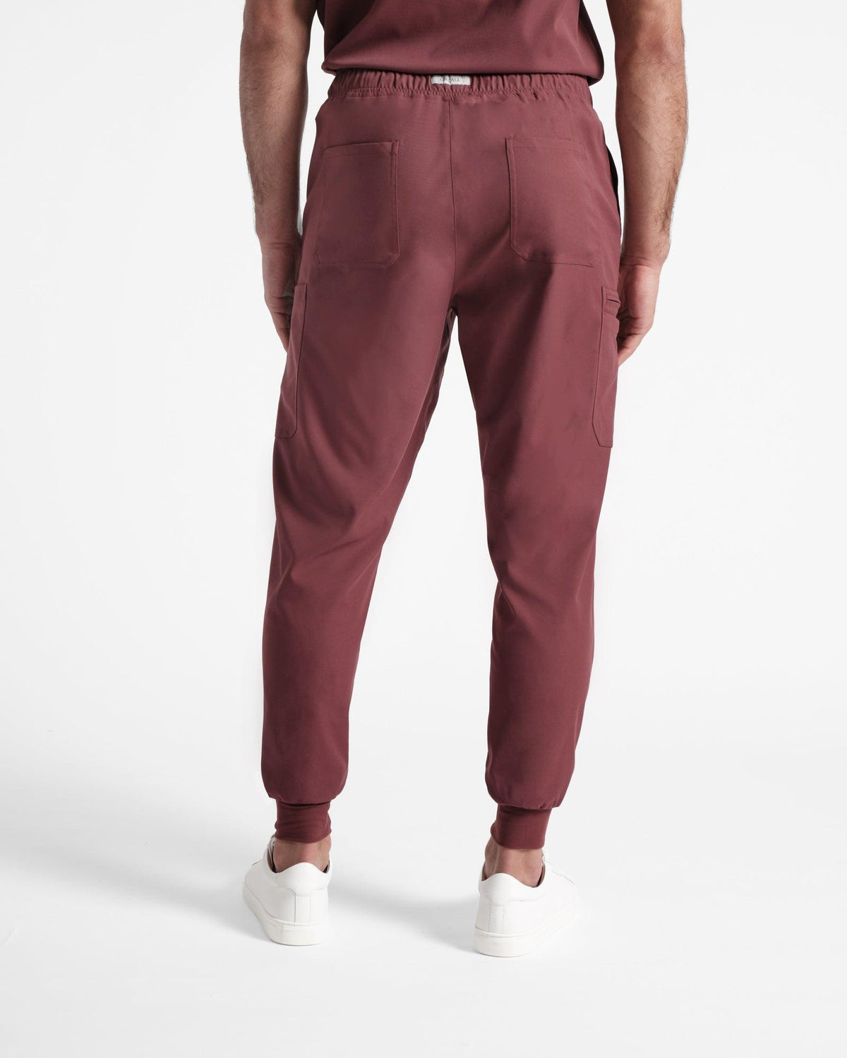 Back side view of man in deep red cargo jogger scrub pants with two back pockets.