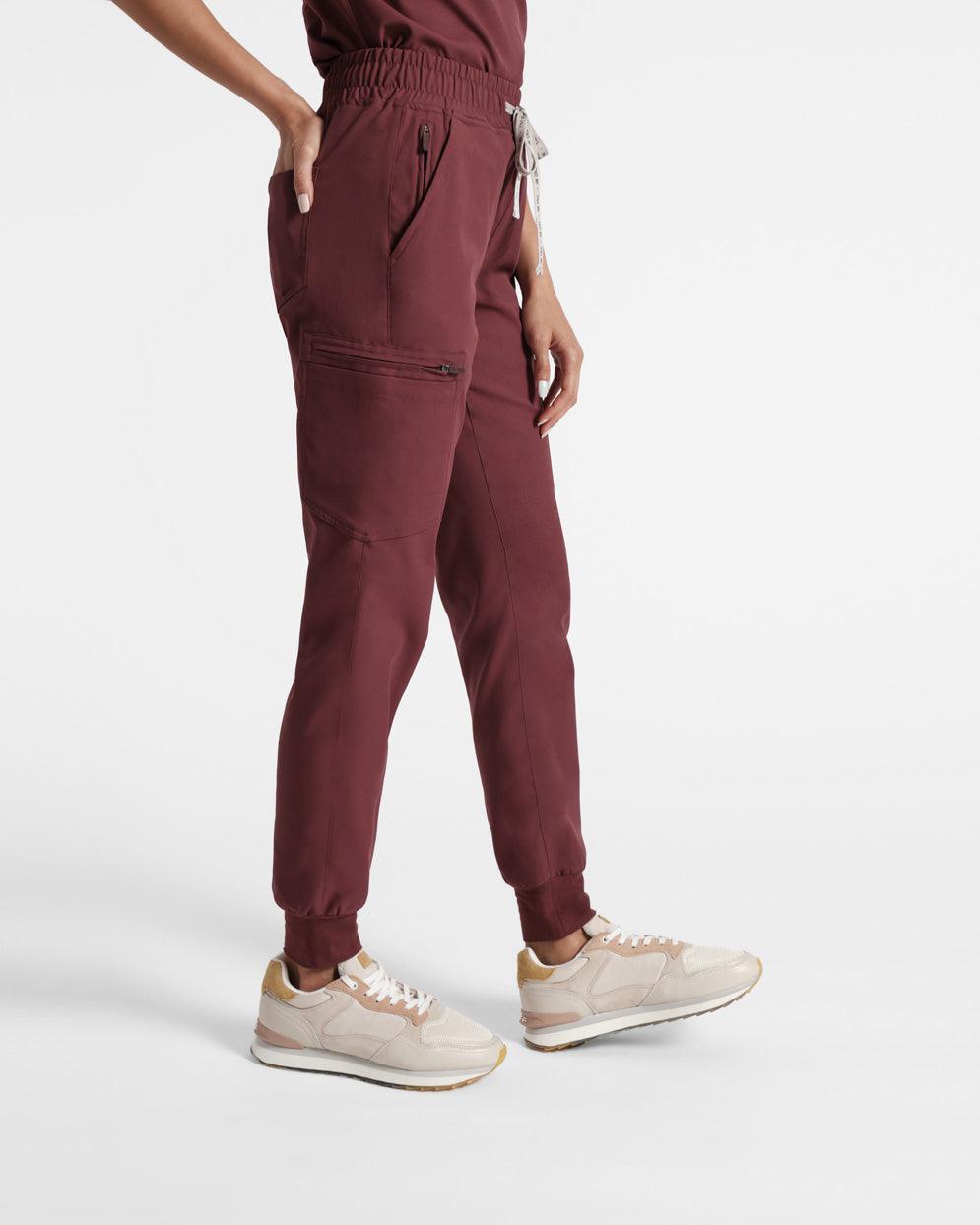 Side view of a model from the waist down in deep red jogger cargo scrub pants with soft ribbed ankle cuffs.