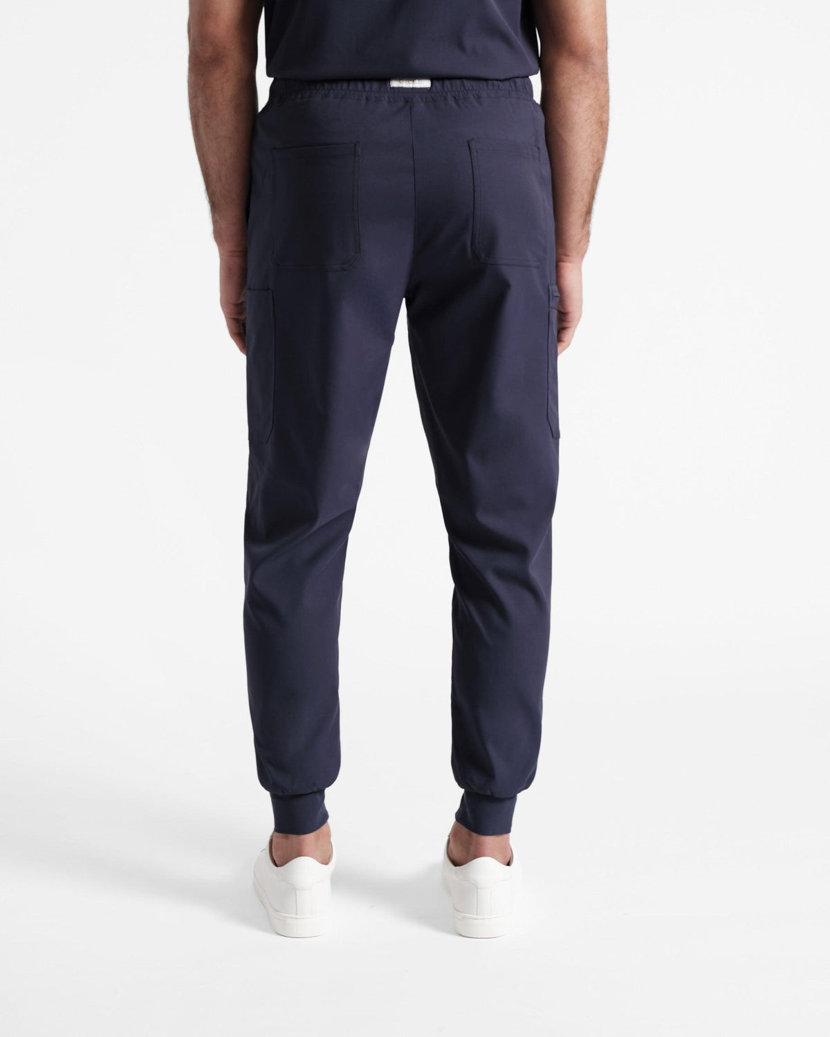 Back side view of man wearing navy cargo jogger scrub pants with two back side pockets.