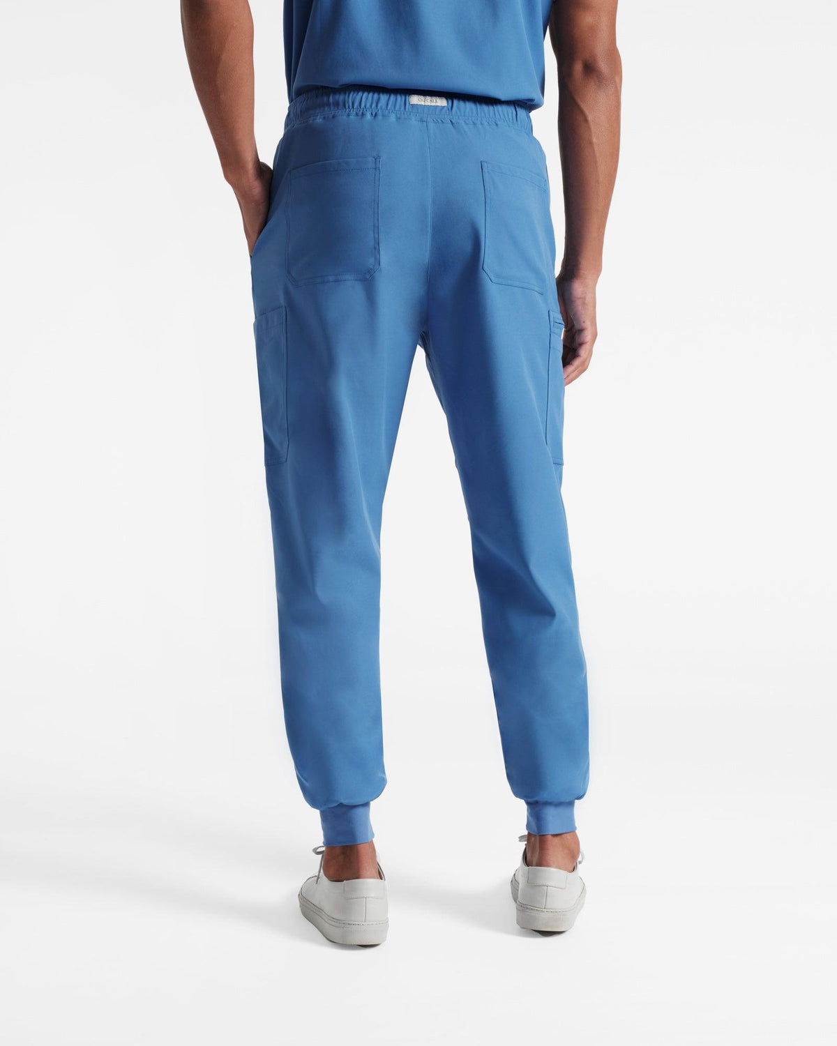 Back side view of man in bright blue cargo jogger scrub pants with two back pockets. 
