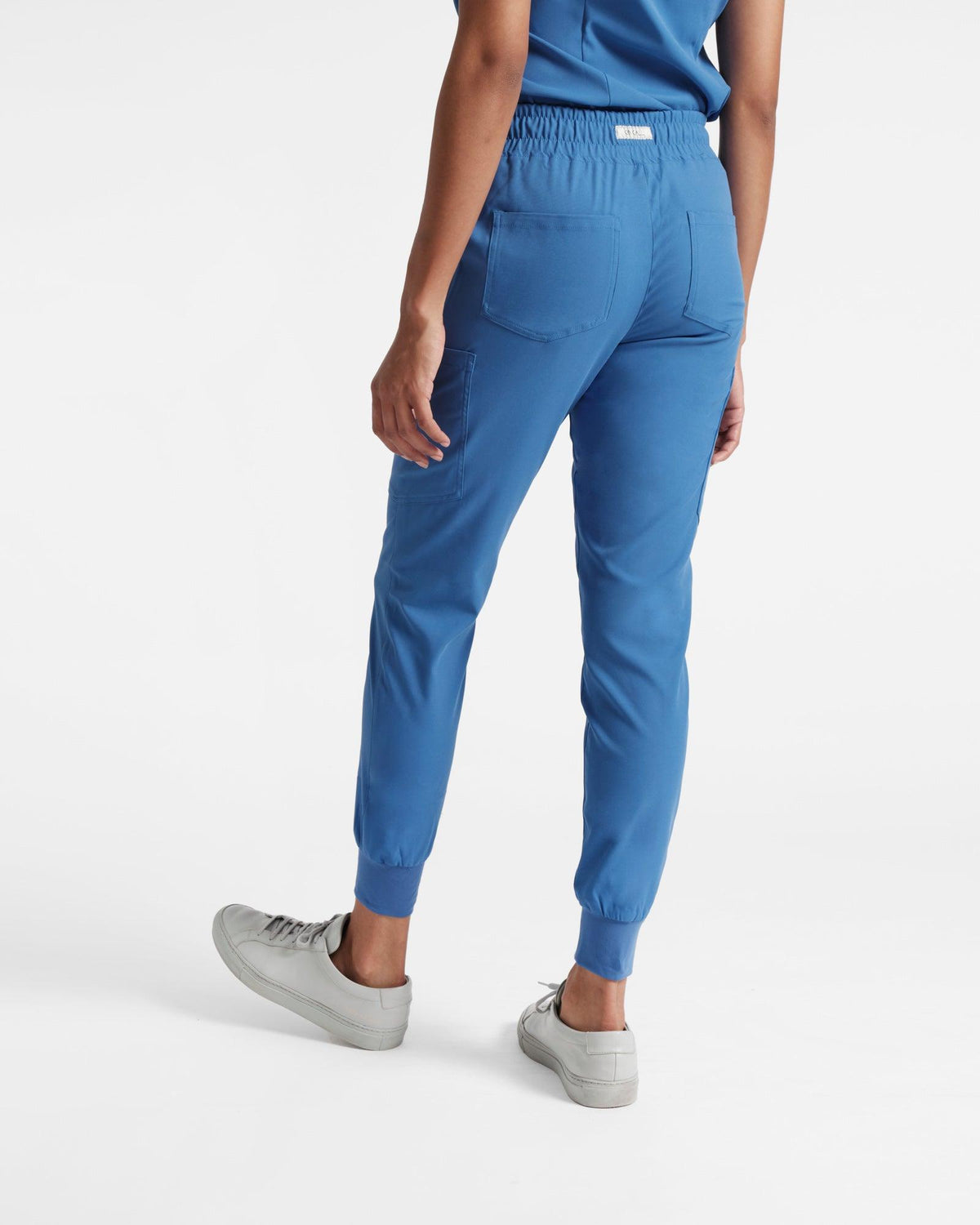 Angled back view of woman in bright blue jogger cargo scrub pants.