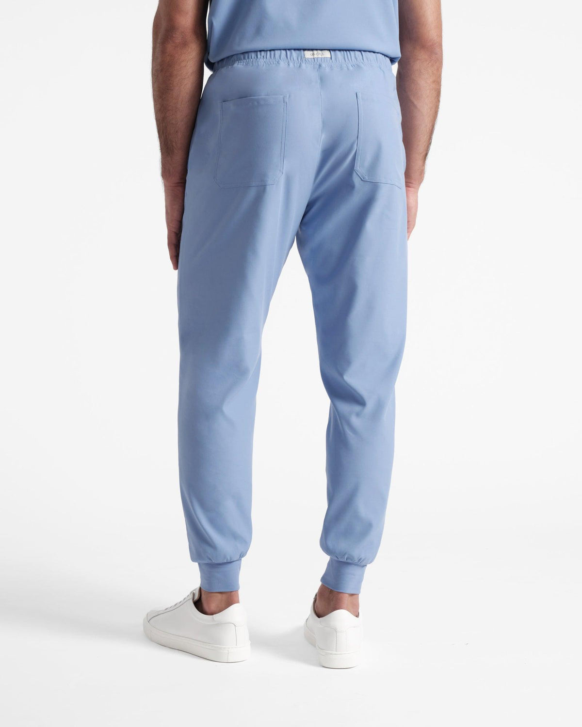 Back side view of man wearing light blue jogger scrub pants with two back pockets.