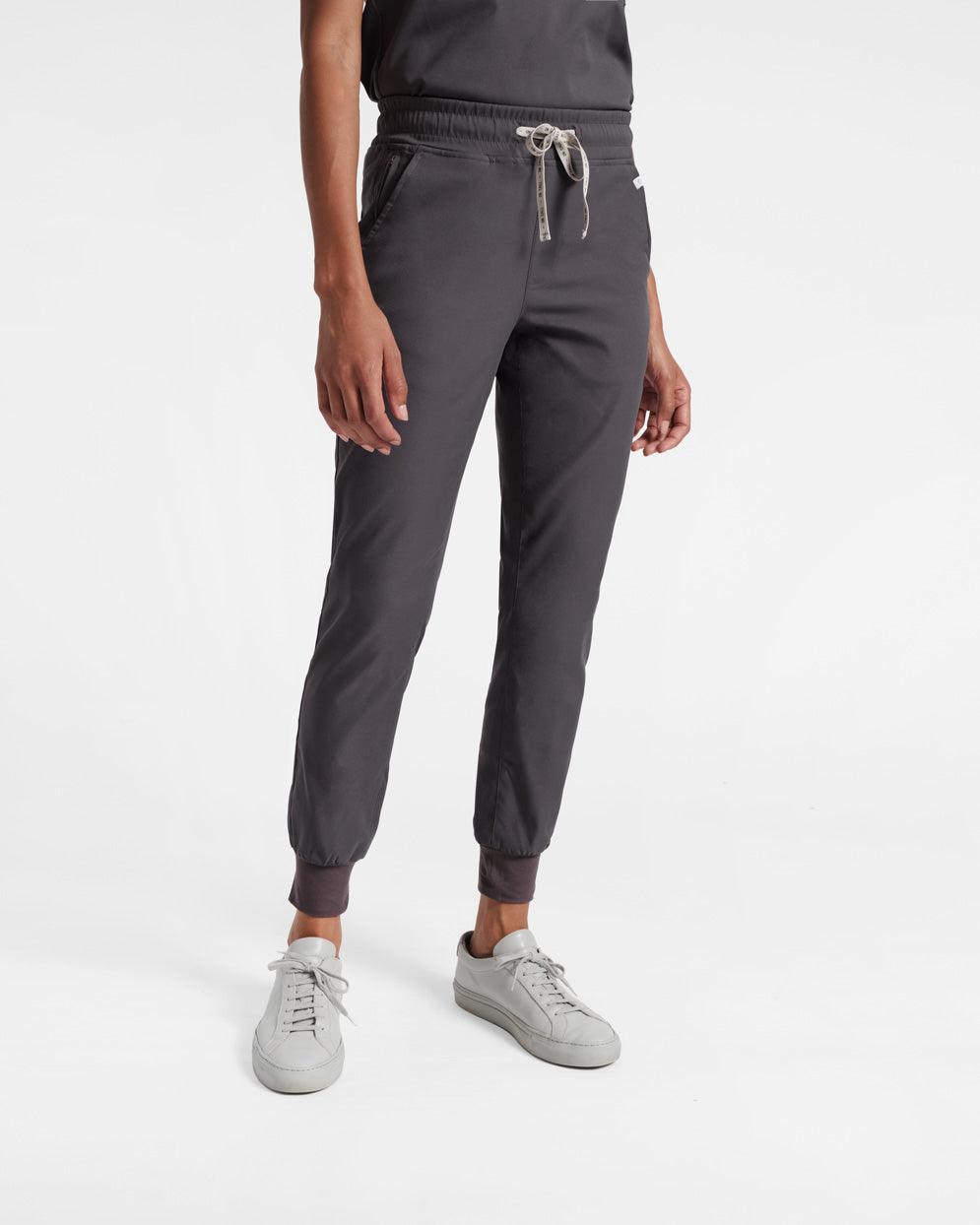 Model from the waist down in women's dark grey jogger scrub pants with soft ribbed ankle cuffs and two waist pockets.
