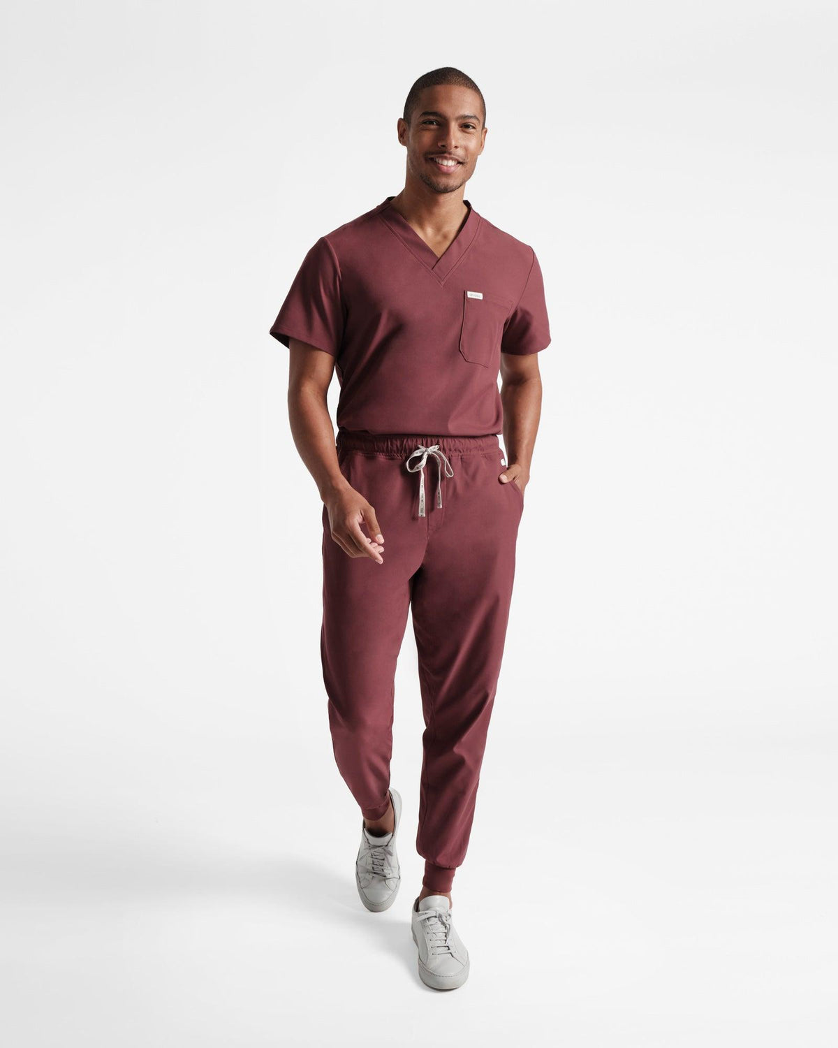 Man in deep red jogger scrub pants and a matching v-neck shirt tucked in.