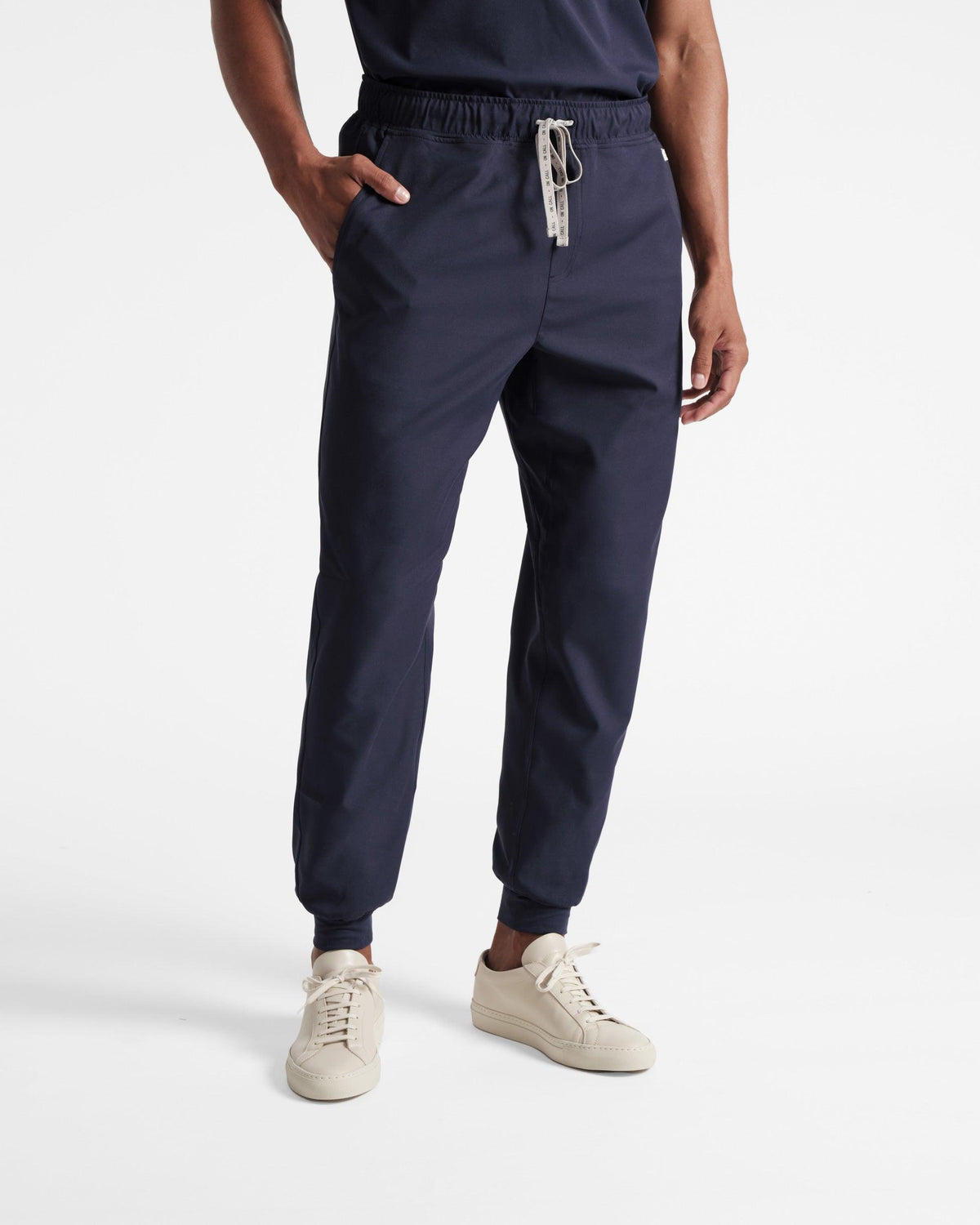Man wearing navy jogger scrub pants with soft ribbed ankle cuffs.