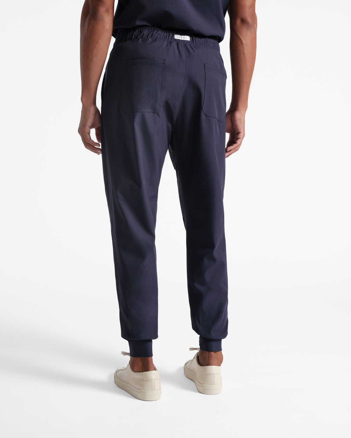 Back side view of man wearing navy jogger scrub pants with two back pockets.
