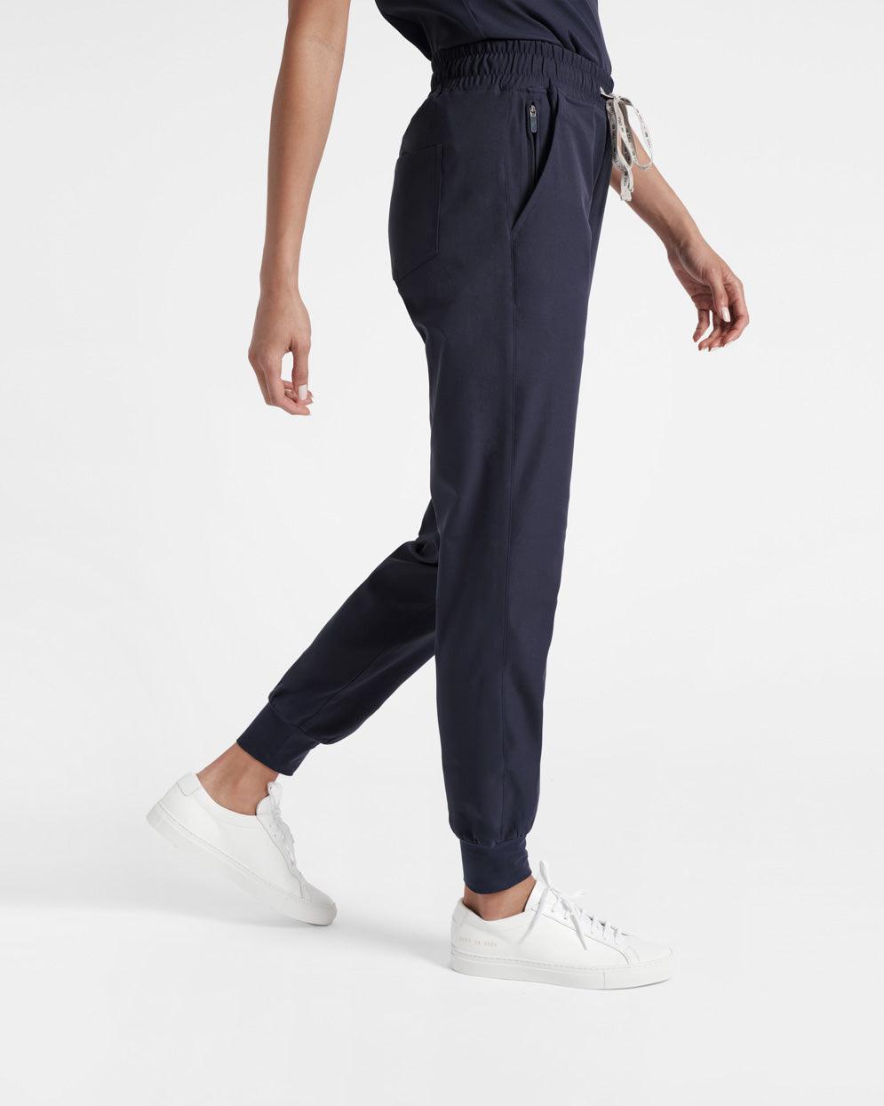Side view of woman in navy jogger scrub pants with soft ribbed ankle cuffs.