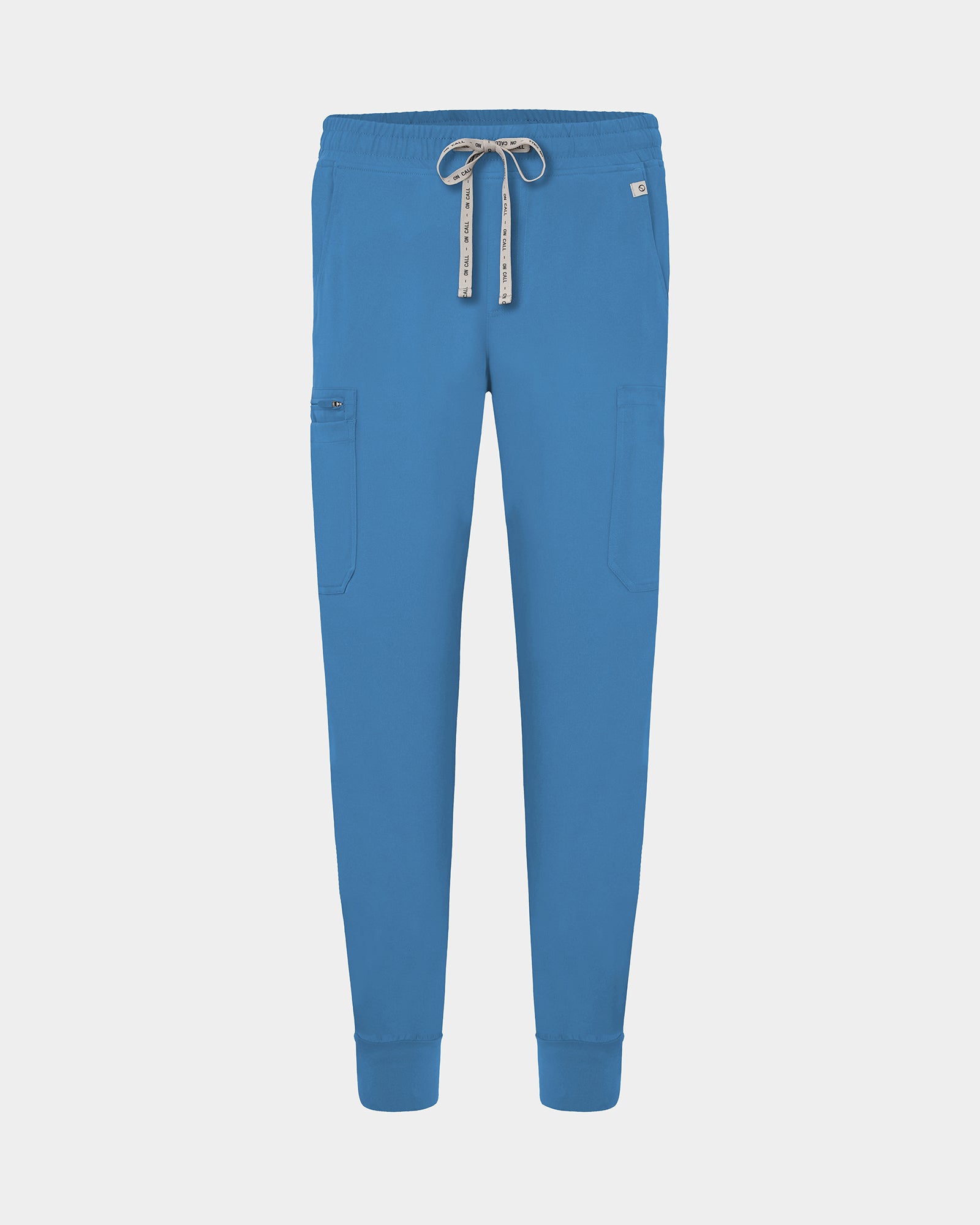 Bright blue scrub pants with a drawstring waist, side cargo pocket, and ribbed ankle cuffs, shown on a light gray background.