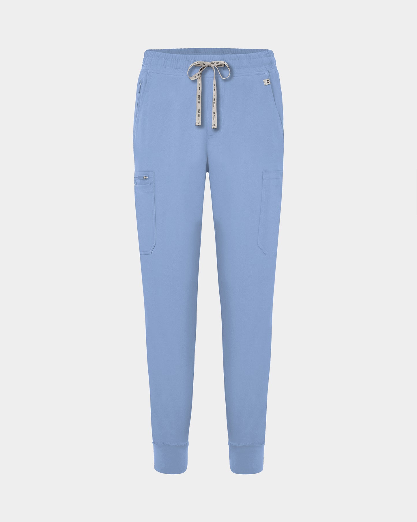 Light blue jogger-style scrub pants with a white drawstring, cargo pockets, and a small white logo on the upper right hip, shown against a light gray background.