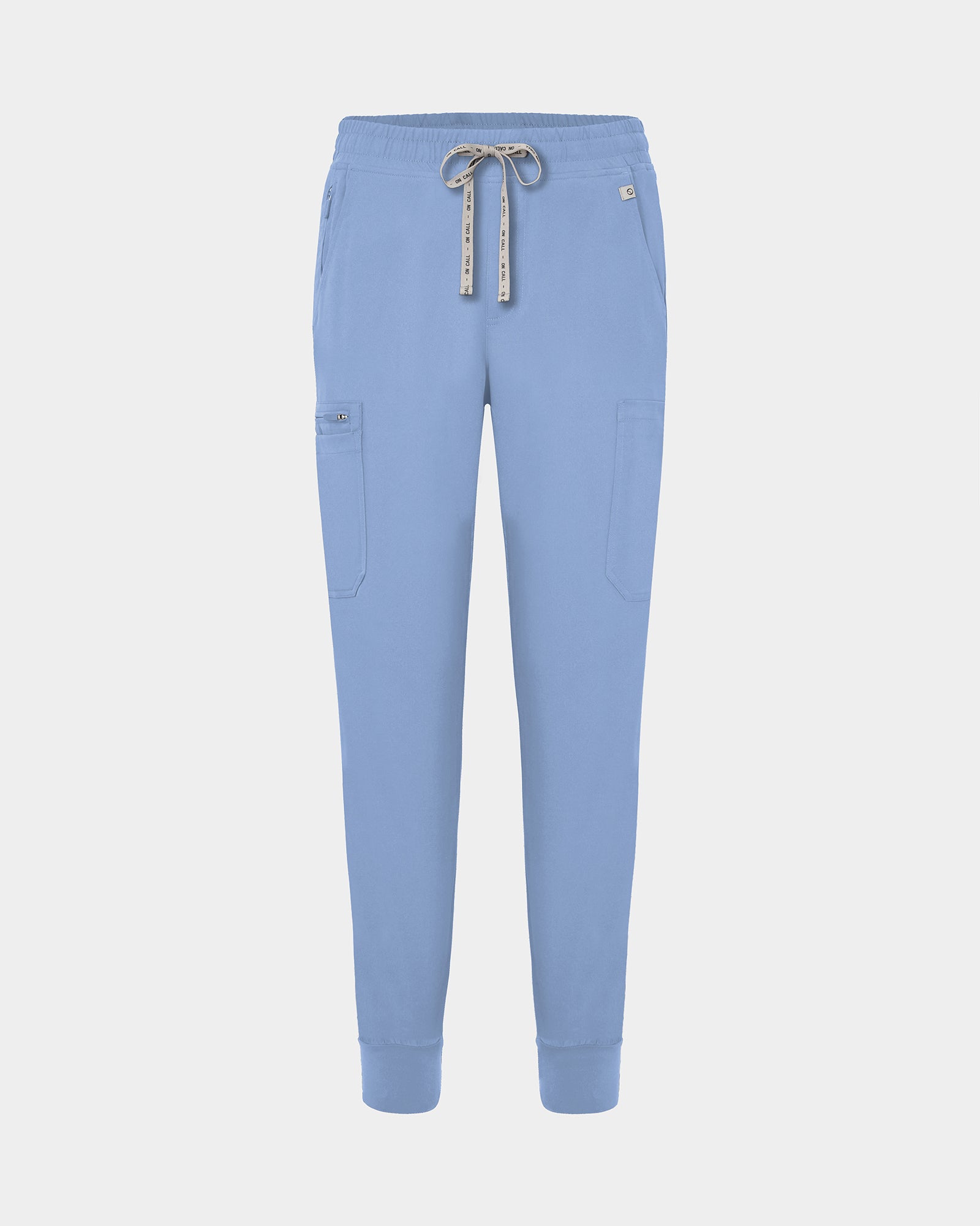 Light blue jogger-style scrub pants with a white drawstring, cargo pockets, and a small white logo on the upper right hip, shown against a light gray background.