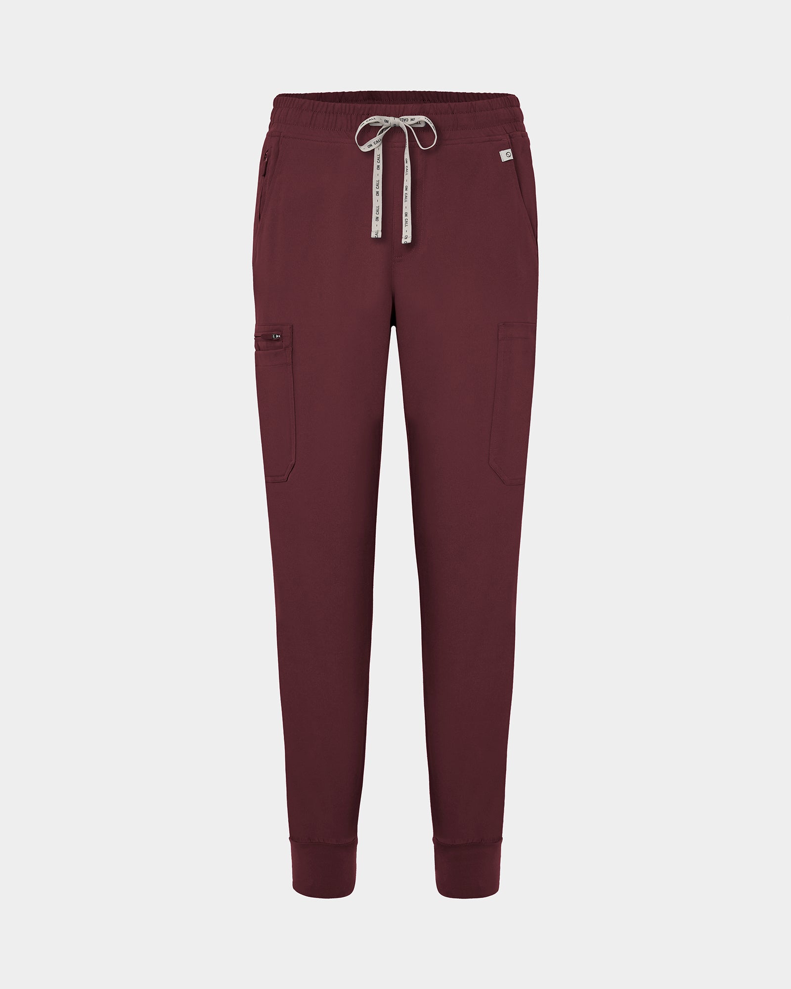 Dark heme red jogger-style scrub pants with a white drawstring, cargo pockets, and a small white logo on the upper right hip, shown against a light gray background.