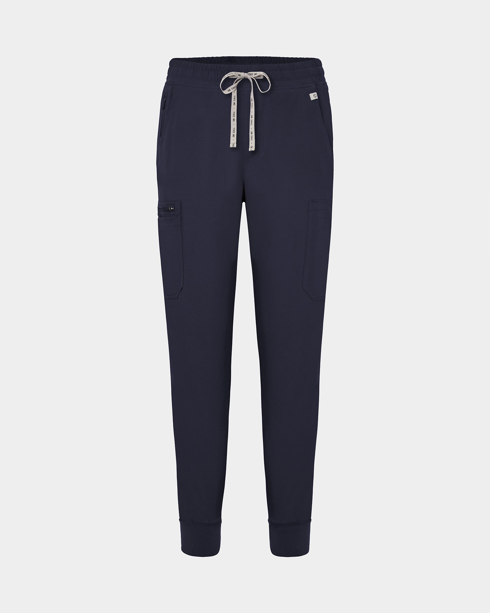 Navy jogger-style scrub pants with a white drawstring, cargo pockets, and a small white logo on the upper right hip, shown against a light gray background.