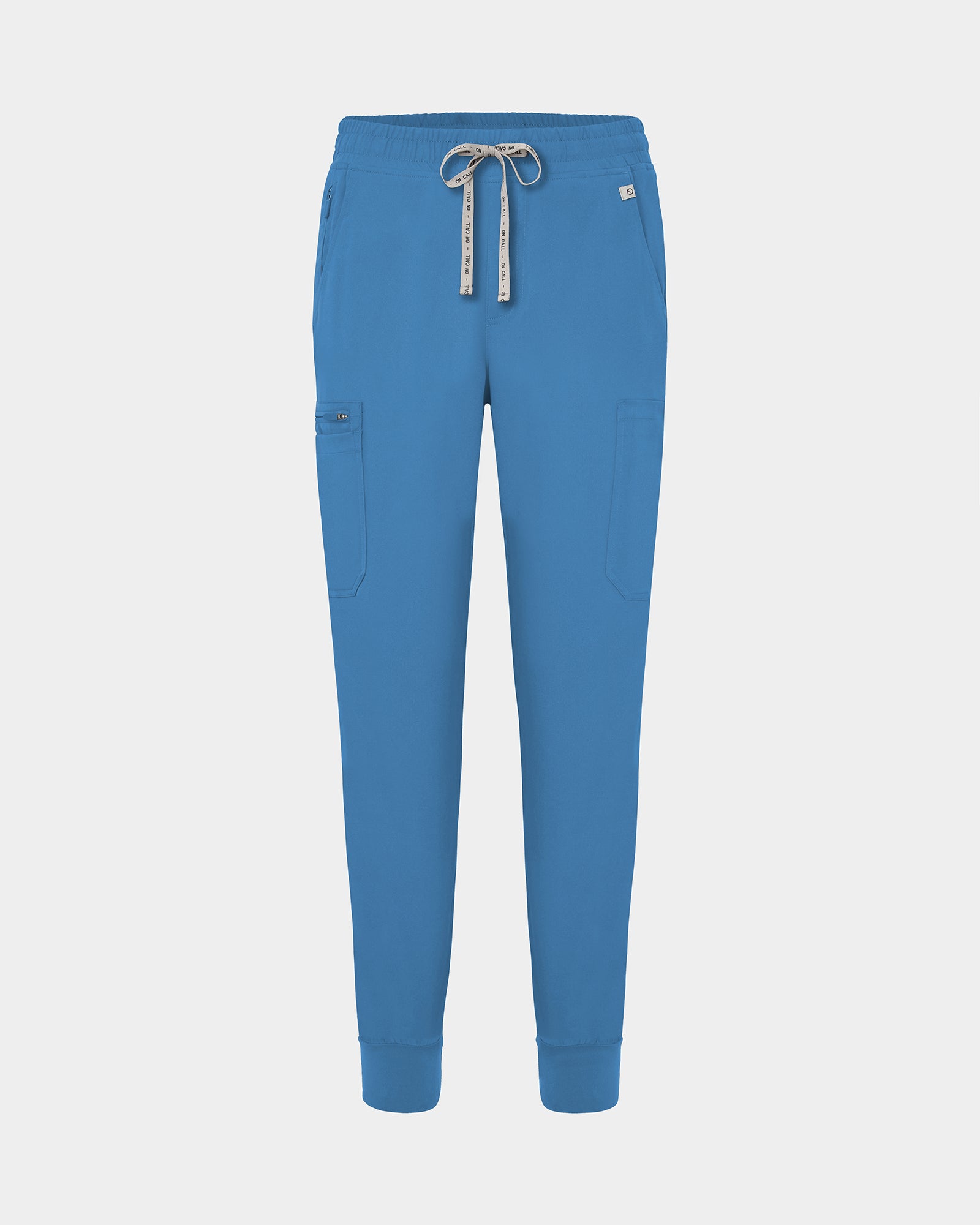 Bright blue jogger-style scrub pants with a white drawstring, cargo pockets, and a small white logo on the upper right hip, shown against a light gray background.
