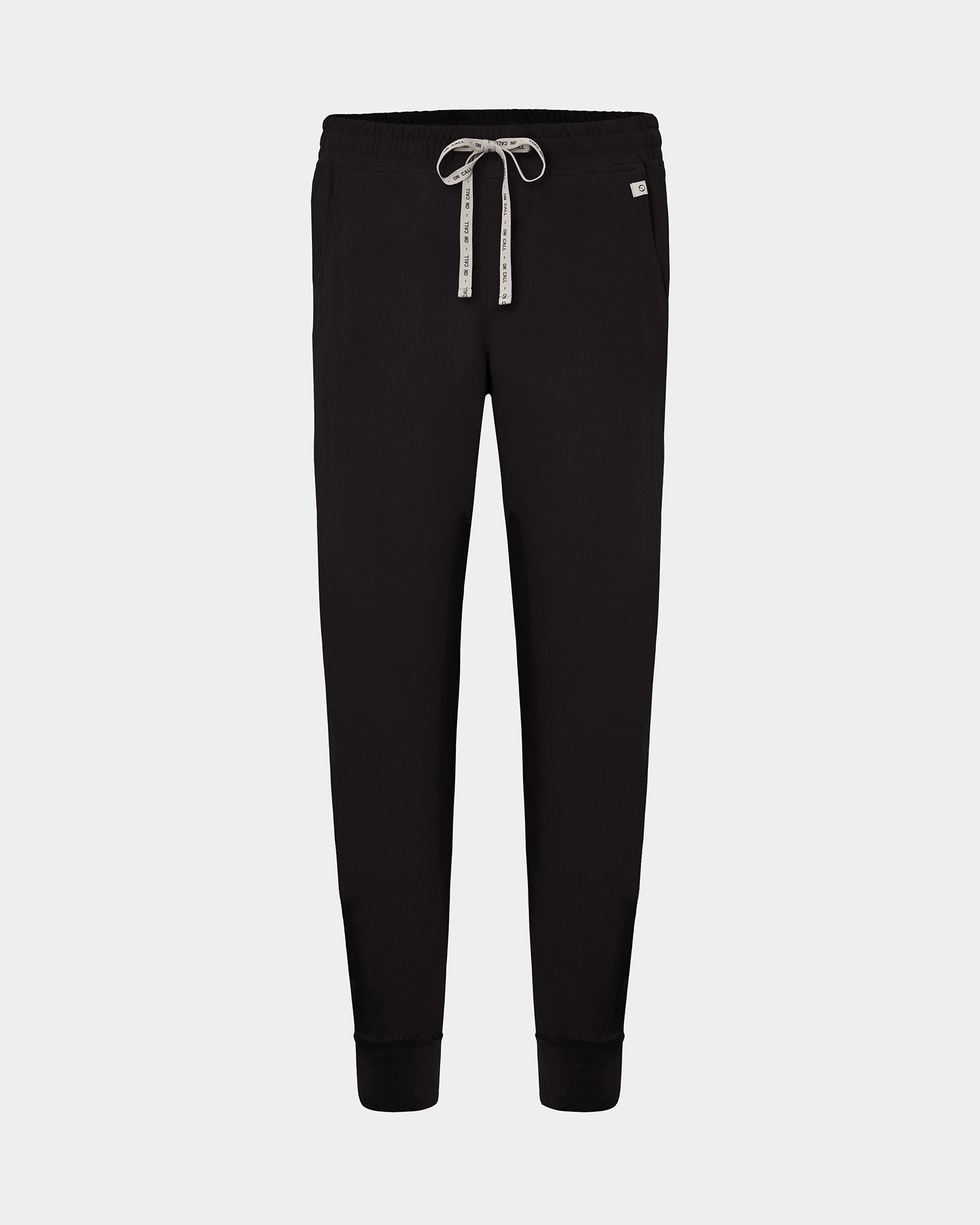 Black jogger scrub pants with a white patterned drawstring and a small white brand tag on the right hip, shown against a light gray background.
