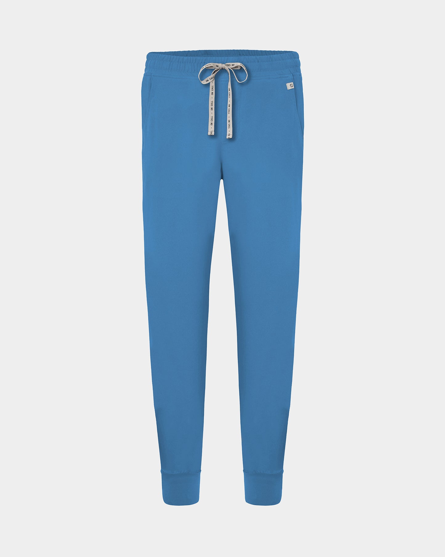 Bright blue jogger-style scrub pants with an elastic waistband, logo drawstring, and ankle cuffs, shown on a light gray background.
