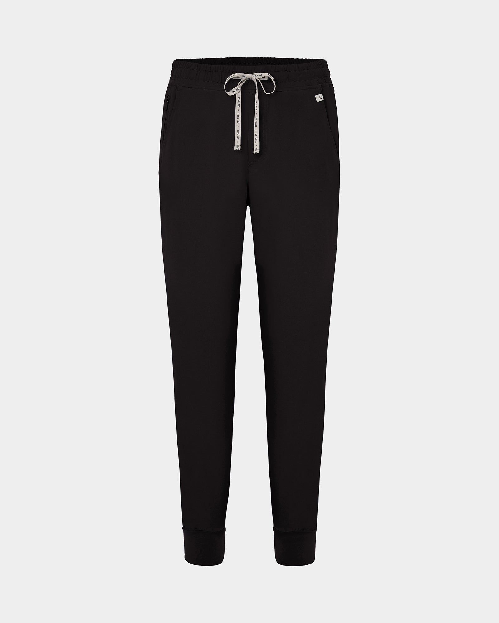 Black jogger scrub pants with a logo drawstring, ankle cuffs, and a small white logo on the left hip, shown against a light gray background.