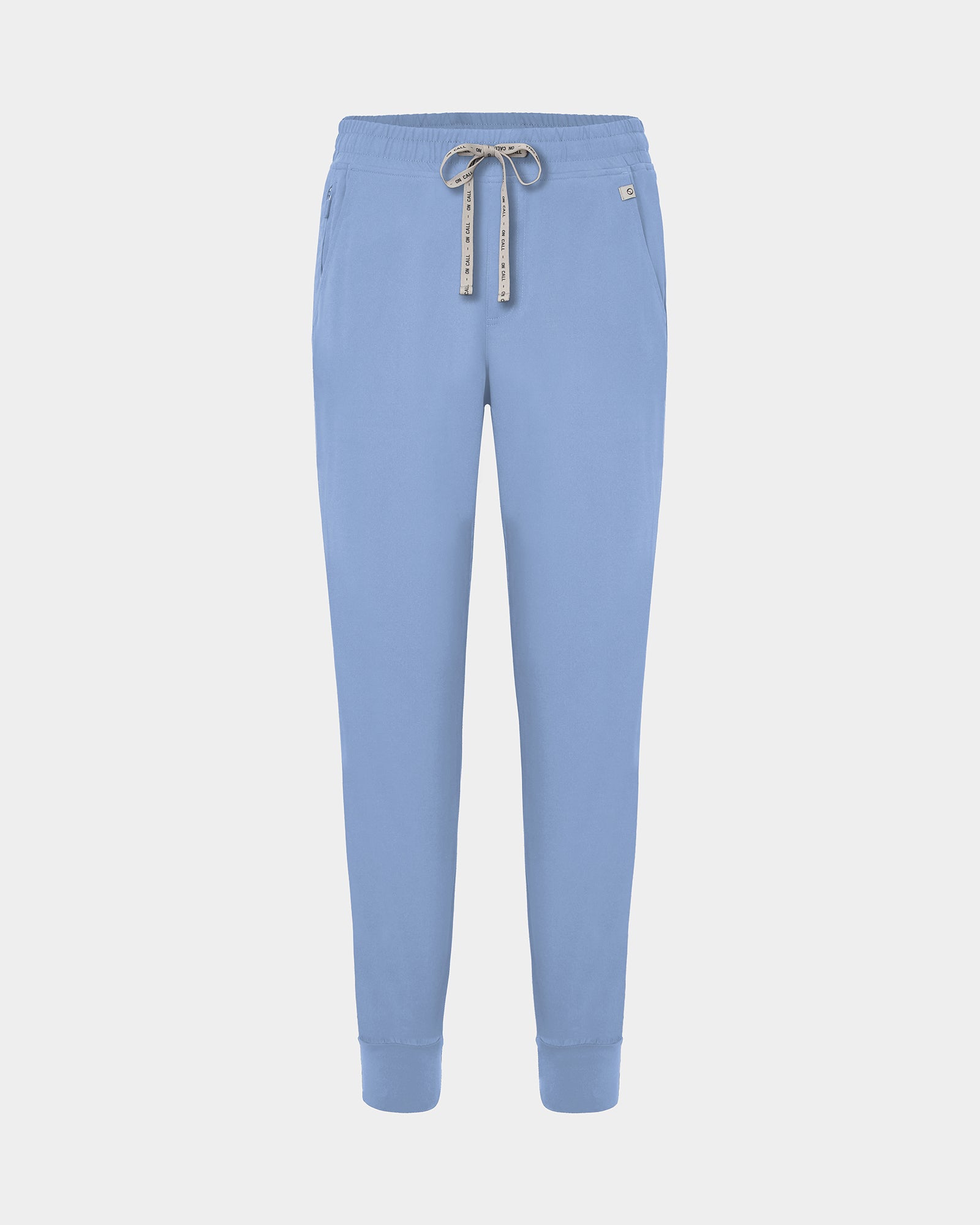 Light blue jogger scrub pants with a logo drawstring, ankle cuffs, and a small white logo on the left hip, shown against a light gray background.