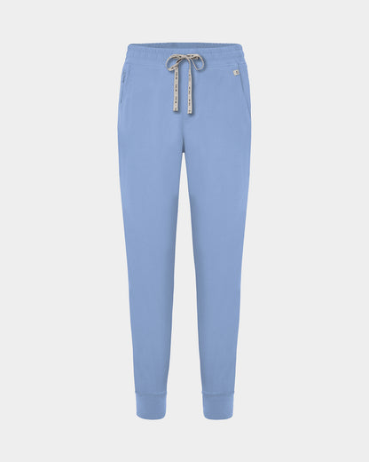 Light blue jogger scrub pants with a logo drawstring, ankle cuffs, and a small white logo on the left hip, shown against a light gray background.